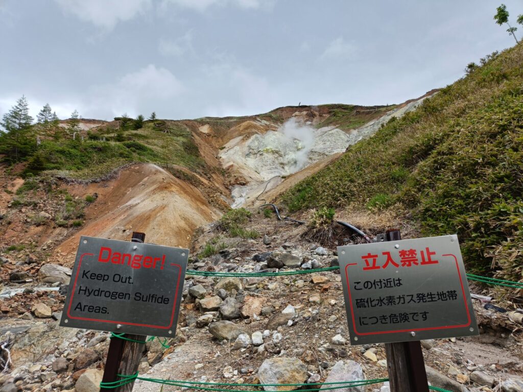 万座温泉の空吹で立ち上る噴気と硫化水素ガスの立入禁止表示