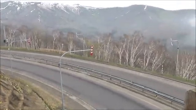日勝峠の展望地点から見えた雪の残る山と道路