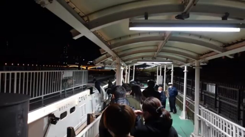 夜の東京水辺ライン船着場で水上バスへ乗船する様子